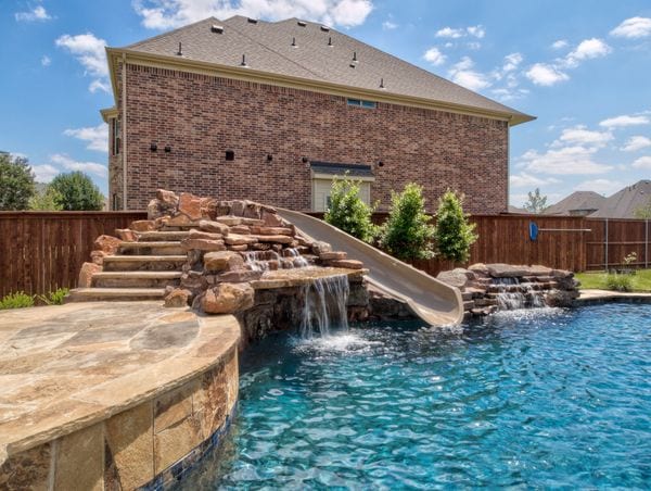 A beautiful pool with a natural looking slide.