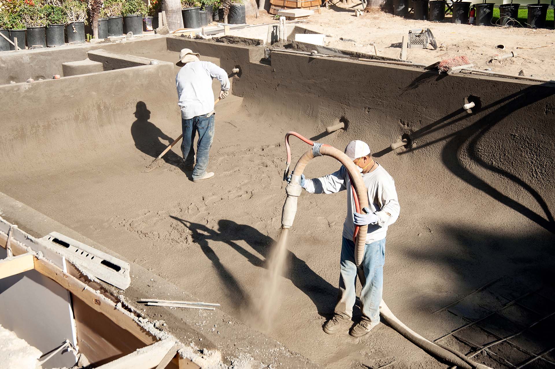 worker spraying gunite on a new pool form